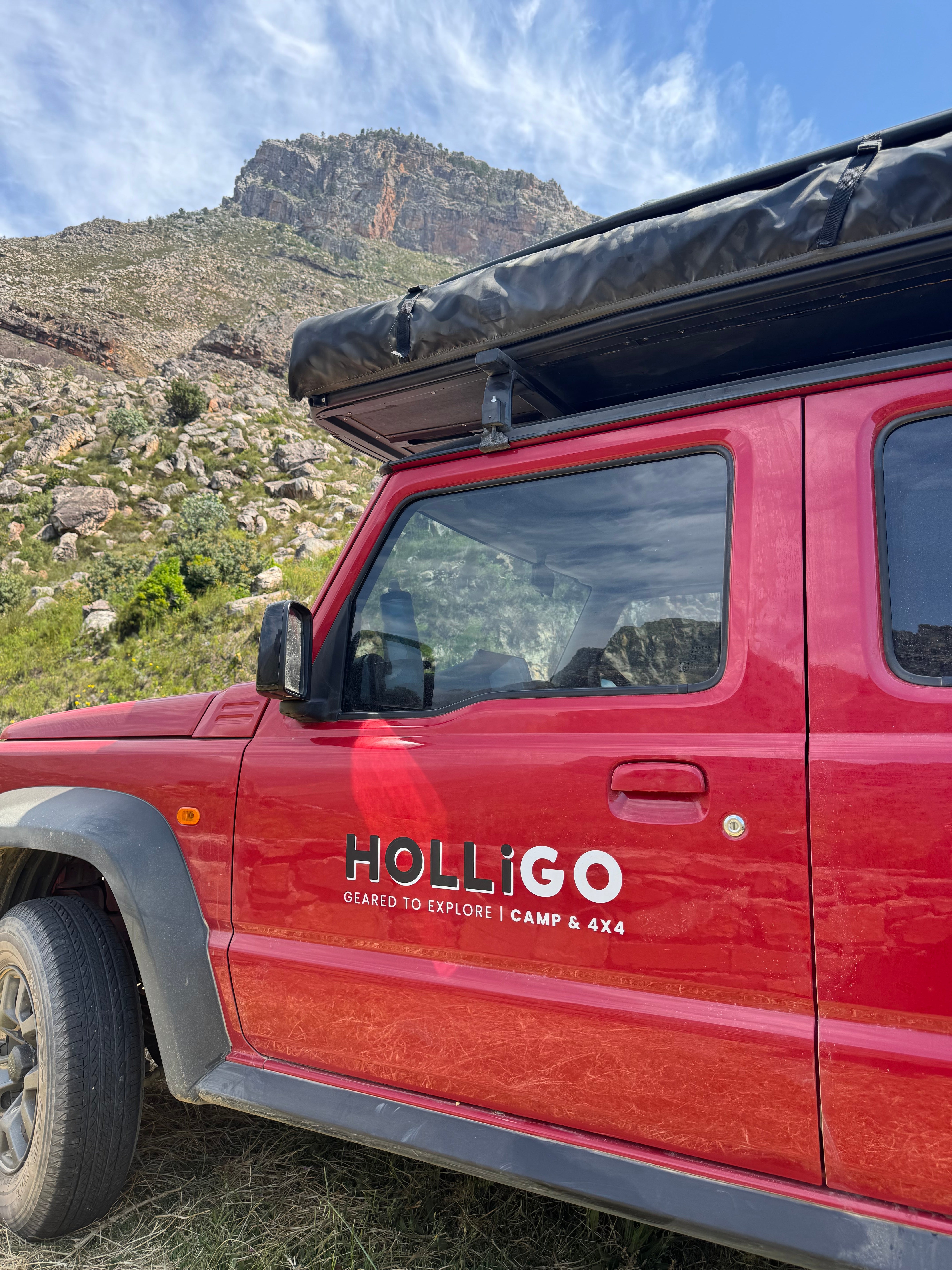 Red vehicle with 'Holligo' branding on a mountainous landscape